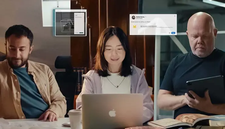 สามคนกำลังทำงานกับแล็ปท็อป หนังสือ และแท็บเล็ต โดยมีกราฟิกอินเทอร์เฟซดิจิทัลแสดงอยู่เหนือพวกเขา